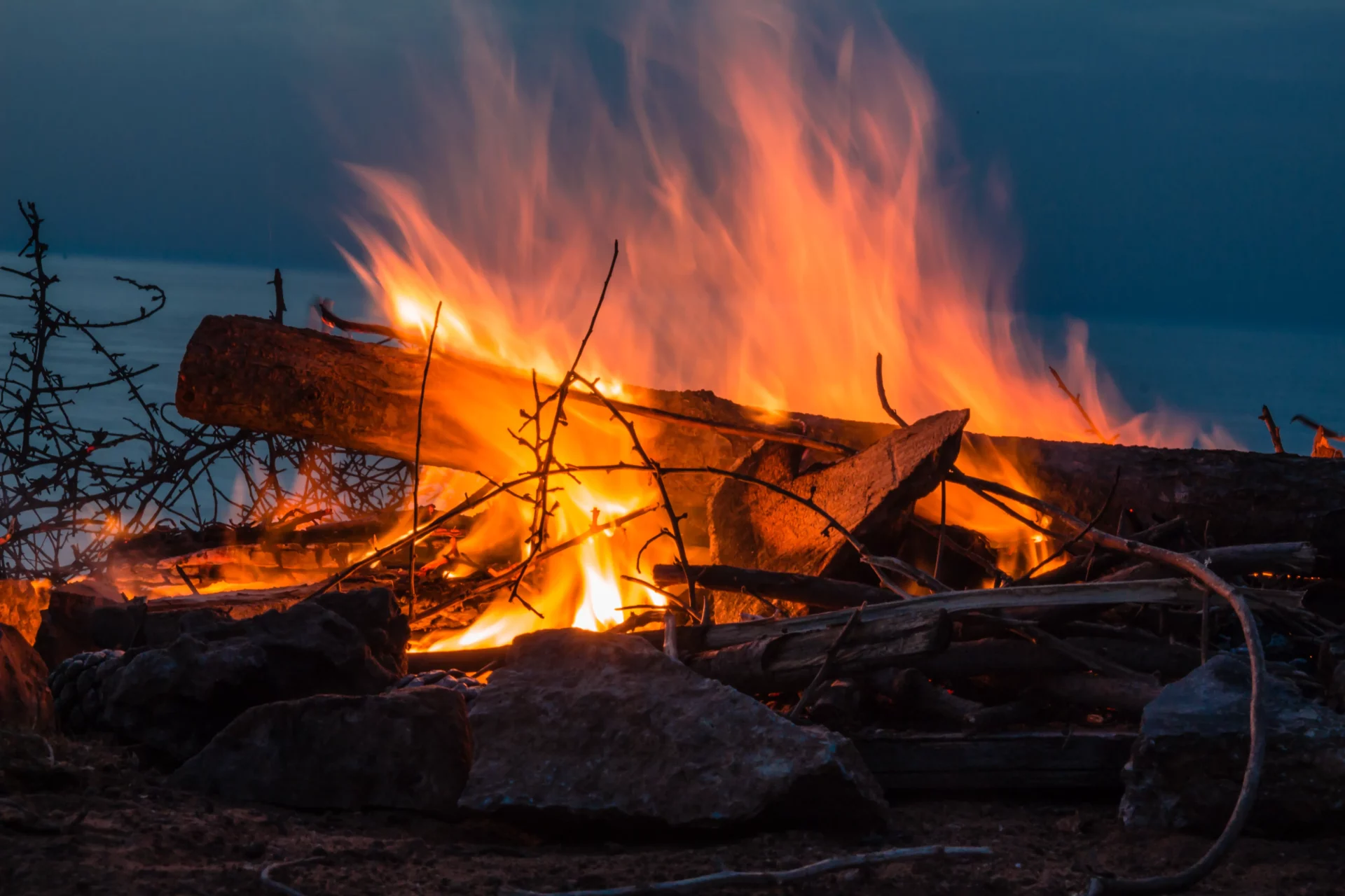 A campfire burning with a lake in the background