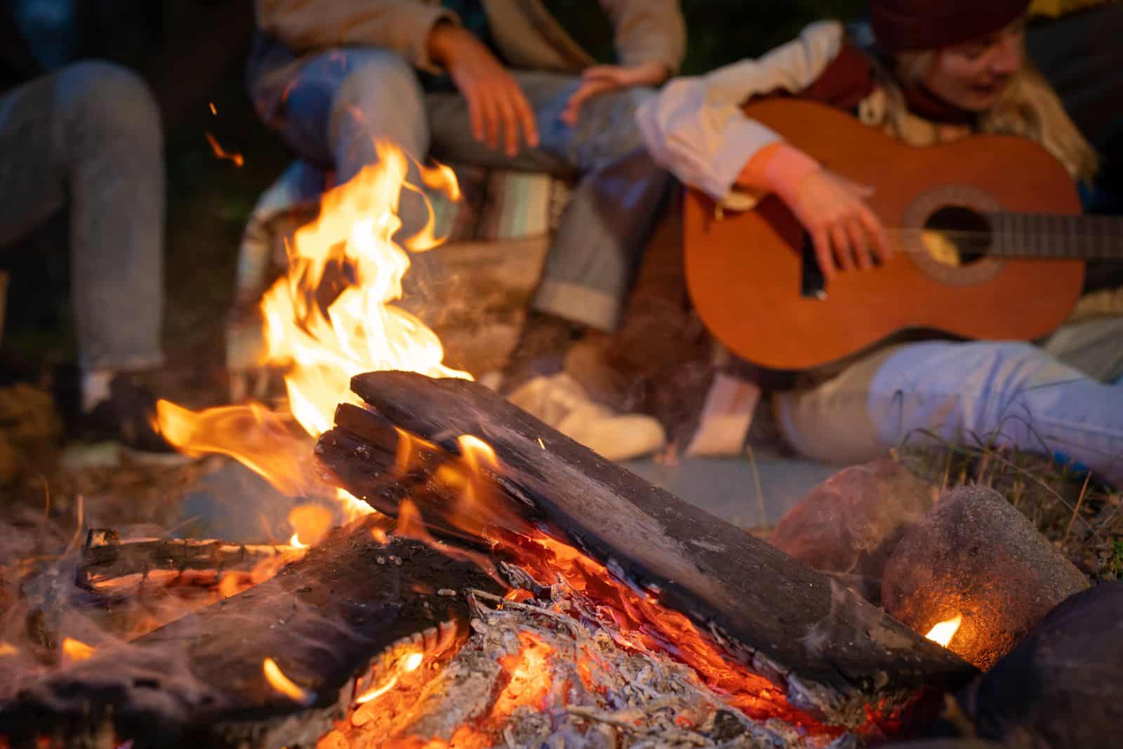 people around a campfire playing guitar